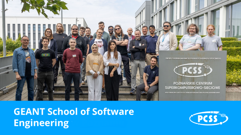There is a large group of people gathered outdoors in front of a modern building. They are clearly posing for a photo. The group appears diverse in age and gender, with most individuals dressed in casual attire. A sign with the acronym "PCSS" and "POZNAŃSKIE CENTRUM SUPERKOMPUTEROWO-SIECIOWE" is visible on the right, suggesting the location is the Poznań Supercomputing and Networking Center.