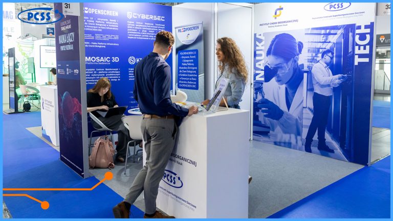 This image depicts a bustling exhibition hall, likely at a technology or scientific fair. In the foreground, a man in a blue shirt and grey trousers is leaning on a white display counter, engaging in conversation with a woman. Behind them, several exhibition booths are visible, featuring large blue and white graphics and text, with some showcasing "OPENSCREEN" and "CYBERSEC" branding. Another prominent booth has large visuals of people working in scientific or technical settings, with the words "NAUKA" (science) and "TECH" displayed vertically. The overall impression is one of active networking and information exchange in a professional setting.